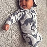 Nyaire joined the competition — help win amazing prizes! baby, infant, carpet, clothing, hoodie, dinosaur_pattern, cute, child, lying_down, smiling, indoor, soft_texture, cozy, sock, young_child, portrait, casual, relaxed, small_person, happy