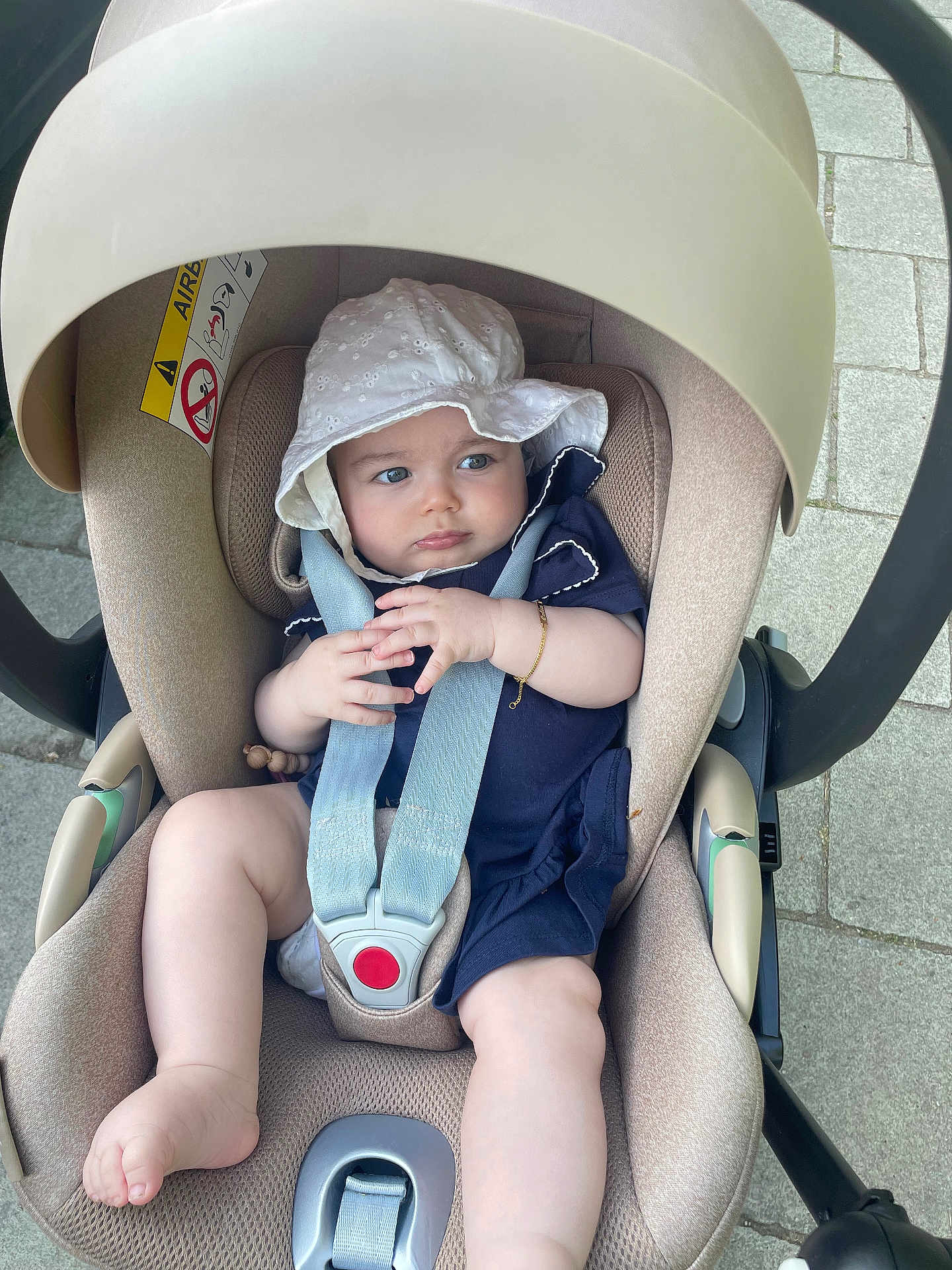Celia a rejoint le concours — aidez-le/la à gagner de superbes lots ! baby, infant, car_seat, stroller, hat, white_hat, navy_blue_clothing, safety_straps, pavement, outdoor, child, cute, plush, seat, foot, hand, face, expression, sunhat, baby_bracelet