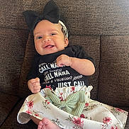 Alanah is registered to the contest to win money with this photo: baby, smiling, headband, bow, couch, clothing, skirt, floral, foot, happy, infant, child, portrait, indoors, cute, sitting, person, tshirt, playful, young_child