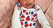 Leila is registered to the contest to win money with this photo: baby, infant, smiling, red_headband, flower_headband, floral_outfit, long_sleeve_shirt, pink_blanket, sitting, cute, happy, child, indoors, soft_texture, patterned_blanket, portrait, apparel, sock, skin, person