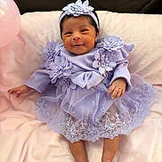 Leila is registered to the contest to win money with this photo: baby, infant, smiling, dress, lavender, headband, flower, applique, blanket, pink, soft, cute, newborn, portrait, happy, clothing, sitting, indoors, person, babywear