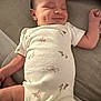 Ireland is registered to the contest to win money with this photo: baby, smiling, sleeping, infant, onesie, clothing, cute, peaceful, lying_down, soft_surface, animal_prints, newborn, happy, child, indoor, person, skin, face, arm, hand