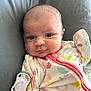 baby, infant, face, pacifier, onesie, clothing, cute, child, expression, lying_down, pink, patterned_clothing, soft_toys, comfort, indoor, young_child, cushion, closeup, skin, newborn