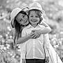 child, children, boy, girl, hat, embrace, smile, happy, outdoor, field, nature, sunlight, black_and_white, portrait, jeans, dress, person, friendship, affection, grass