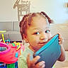 Nicholas is registered to the contest to win money with this photo: toddler, child, indoor, tablet, braided_hair, smiling, toy, play, colorful, living_room, furniture, chair, sofa, giraffe_wall_art, person, cute, happy, young_child, playful, home