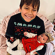 Dayton is registered to the contest to win money with this photo: child, baby, smiling, happy, holding, sweater, holiday_clothing, headband, blanket, indoor, portrait, candid, family, toddler, seated, cute, hands, face, person, warm