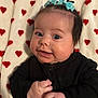 baby, infant, face, smile, black_clothing, blue_bow, blanket, hearts, cute, child, portrait, happy, skin, hands, lying_down, indoor, person, young, closeup, warm