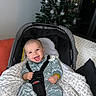 Lizio participe au concours pour gagner de l'argent avec cette photo : baby, car_seat, smiling, dinosaur_outfit, blanket, christmas_tree, ornaments, indoors, happy, child, cushion, holiday, infant, clothing, seatbelt, pacifier_clip, person, cozy, furniture, decor