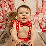 baby, infant, smile, bow_tie, suspenders, disco_ball, teddy_bear, hearts, backdrop, bows, studio_shot, portrait, red_color, festive, sitting, wooden_floor, cute, chubby_cheeks, props, celebration