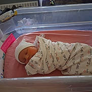 Aerial joined the competition — help win amazing prizes! newborn, baby, infant, swaddled, blanket, hospital, bassinet, sleeping, pink, hat, peaceful, child, bed, mattress, person, indoor, closeup, cute, resting, hospital_room