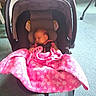 baby, car_seat, blanket, pink, sleeping, infant, child, indoors, floor, carrying_handle, clothing, head_support, person, toddler, floral_pattern, fabric, comfort, rest, seat, quiet