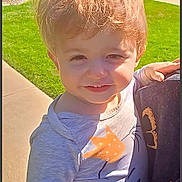 Adonis is registered to the contest to win money with this photo: child, boy, toddler, smiling, face, portrait, outdoor, sunlight, grass, lawn, sidewalk, house, apartment, hair, blond_hair, long_sleeve_shirt, dinosaur_shirt, person, being_held, daytime