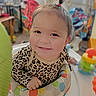 baby, child, infant, smiling, portrait, face, indoors, playroom, activity_seat, toy, colorful, leopard_print, clothing, sitting, happy, playful, home, furniture, close_up, photography