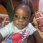 Jah'Shaun joined the competition — help win amazing prizes! toddler, child, person, bed, bedspread, pattern, clothing, shirt, spiderman, indoor, portrait, face, hand, curious, expression, young_child, black_hair, sitting, adult, necklace