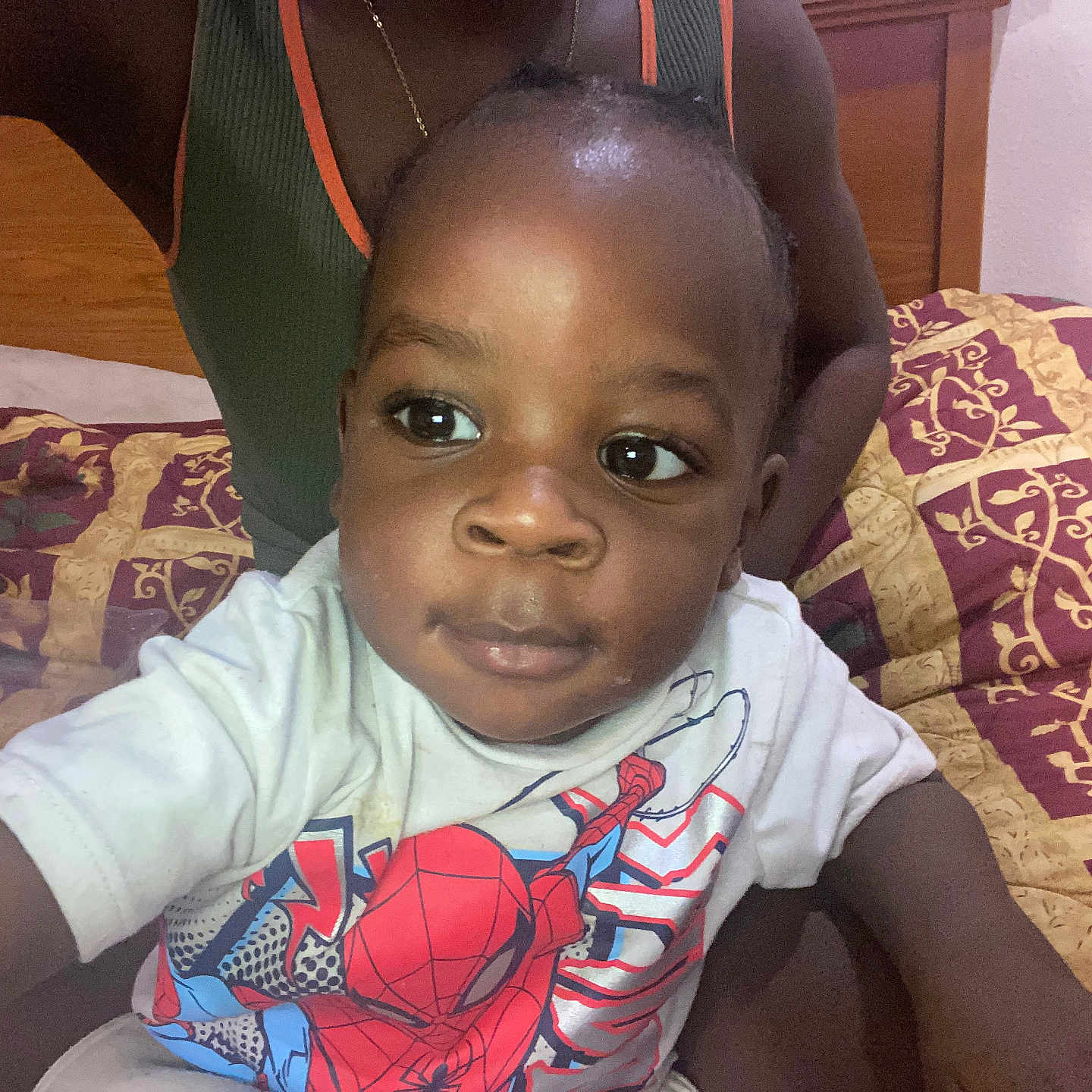 Jah'Shaun joined the competition — help win amazing prizes! toddler, child, person, bed, bedspread, pattern, clothing, shirt, spiderman, indoor, portrait, face, hand, curious, expression, young_child, black_hair, sitting, adult, necklace