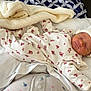newborn, baby, sleeping, hat, blanket, floral_pattern, infant, bed, pillow, cozy, clothing, peaceful, rest, cute, soft, indoors, portrait, child, wrapped, relaxed