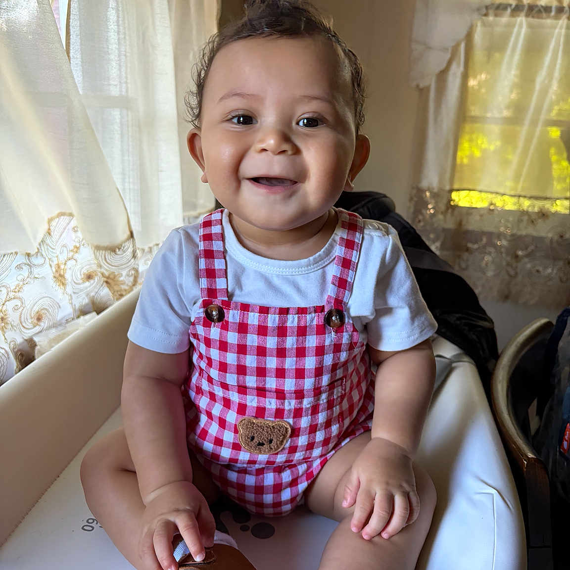 Sasher is registered to the contest to win money with this photo: baby, brown_shoes, checkered_outfit, child, curtains, cute, fashion, happy, high_chair, home, indoors, portrait, red, shoes, sitting, smiling, sunlight, toddler, white, window