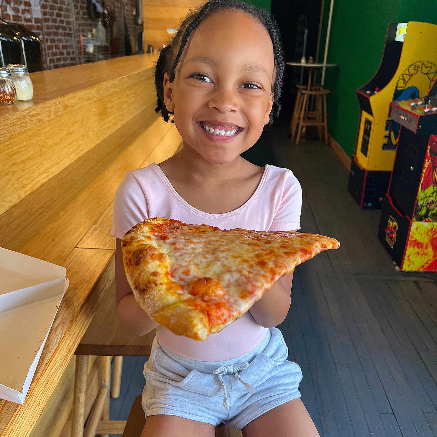 Sophia is registered to the contest to win money with this photo: child, eating, face, female, food, furniture, girl, happy, hardwood, head, indoors, interiordesign, person, photography, pizza, portrait, sitting, smile, table, wood