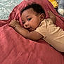 baby, infant, child, blanket, quilt, plush_toy, bracelet, lying_down, indoors, curly_hair, person, cute, soft_lighting, cozy, bedroom, clothing, resting, face, skin, smiling