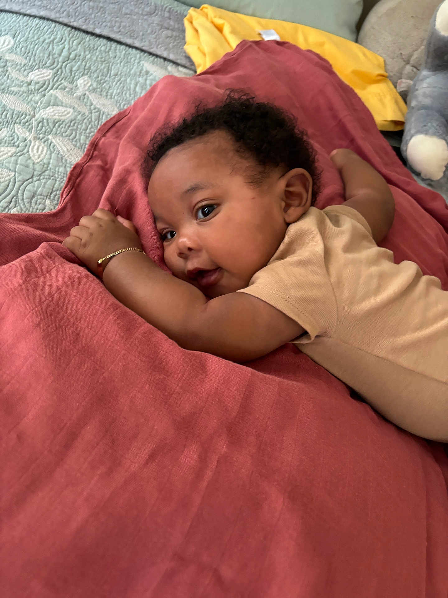 Tafari joined the competition — help win amazing prizes! baby, infant, child, blanket, quilt, plush_toy, bracelet, lying_down, indoors, curly_hair, person, cute, soft_lighting, cozy, bedroom, clothing, resting, face, skin, smiling