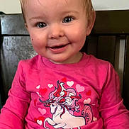 Mia Rose is registered to the contest to win money with this photo: toddler, child, smile, pink_shirt, unicorn, hearts, long_sleeve, indoor, chair, cute, happy, portrait, person, clothing, baby, face, young_child, sitting, casual, bright_colors