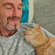 Roxy participe au concours pour gagner de l'argent avec cette photo : man, bald, glasses, cat, orange_cat, pet, couch, smile, indoor, relaxation, affection, casual_clothing, closeup, resting, domestic_animal, human_animal_interaction, happy, portrait, feline, comfort
