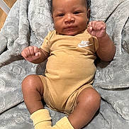 Nyjorrious is registered to the contest to win money with this photo: baby, blanket, child, clothing, comfortable, curly_hair, cute, fists, floor, indoor, infant, laying, legs, nike, onesie, portrait, skin, socks, soft, wooden_floor