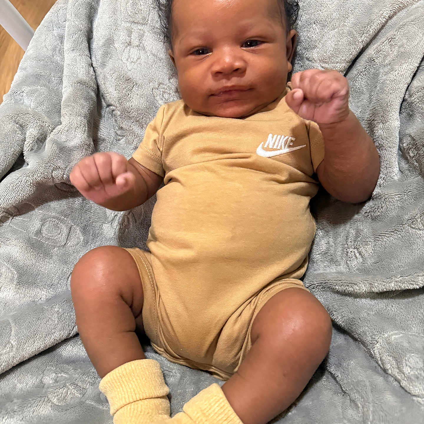Nyjorrious is registered to the contest to win money with this photo: baby, blanket, child, clothing, comfortable, curly_hair, cute, fists, floor, indoor, infant, laying, legs, nike, onesie, portrait, skin, socks, soft, wooden_floor