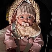 Elona participe au concours pour gagner de l'argent avec cette photo : baby, pacifier, hat, pink_clothing, car_seat, straps, beads, bib, infant, cozy, child, cute, face, hands, sitting, warm, indoors, portrait, headwear, apparel