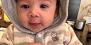 Josiah is registered to the contest to win money with this photo: baby, hoodie, child, face, hands, indoor, computer_monitor, desk, candle, paper, clothing, curious, cute, portrait, sitting, striped, knitwear, owl_emblem, tongue, young_child
