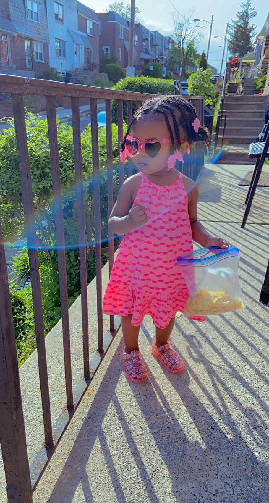 Yuri is registered to the contest to win money with this photo: dress, electric_blue, eyewear, fence, happy, human_leg, leg, leisure, magenta, pattern, person, plant, recreation, sidewalk, standing, street_fashion, sunglasses, toddler, tree, vision_care