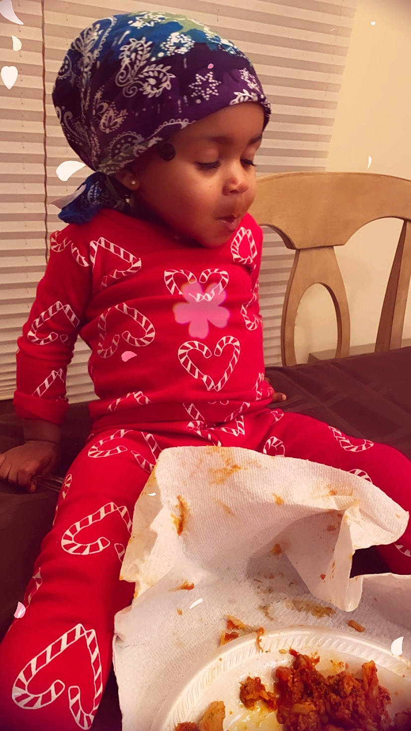 Yuri is registered to the contest to win money with this photo: baby, baby_toddler_clothing, cap, chair, child, cuisine, event, facial_expression, food, happy, headwear, knit_cap, magenta, pattern, person, pink, red, sitting, skin, sleeve