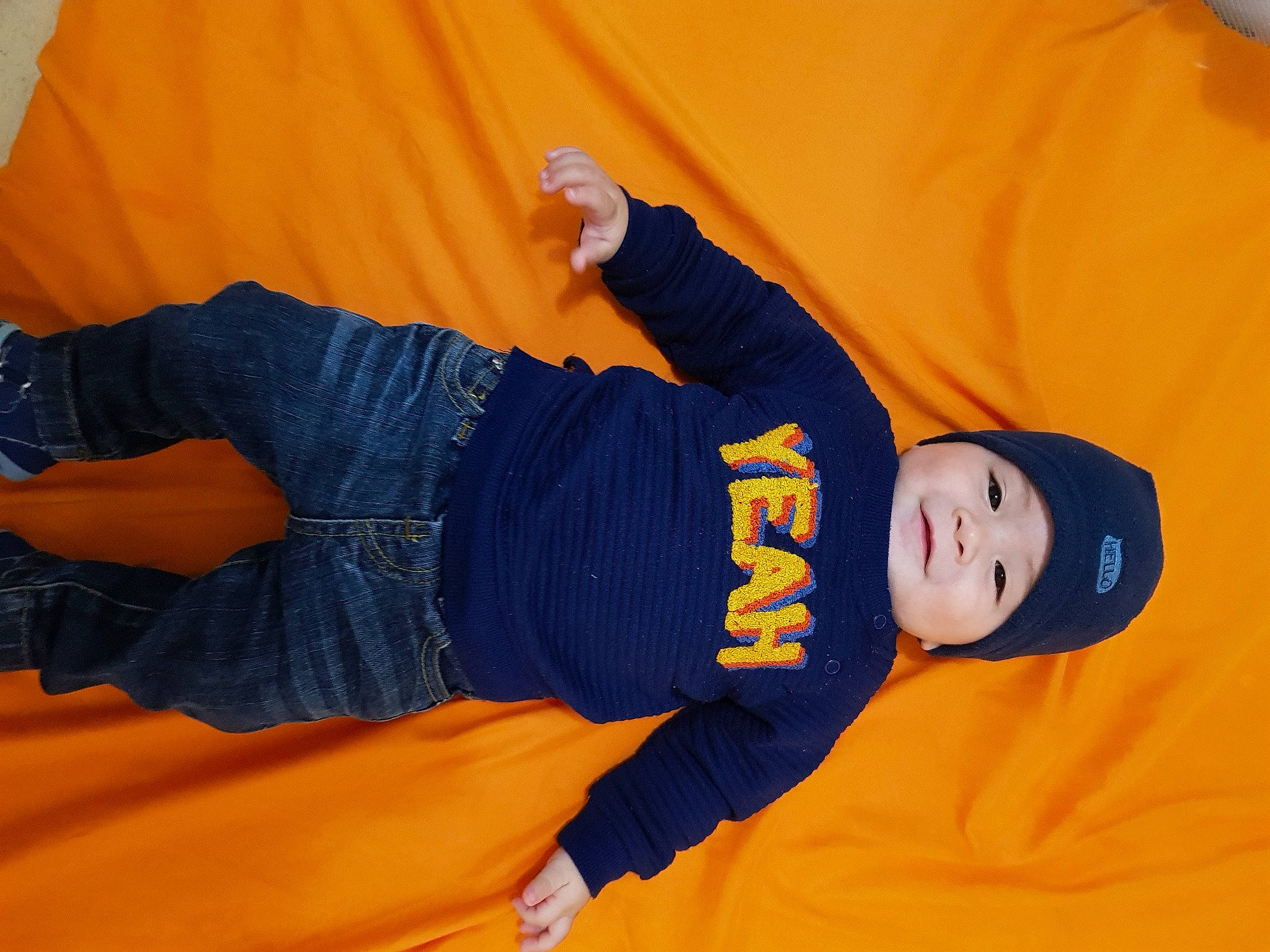 Jerik participe au concours pour gagner de l'argent avec cette photo : arm, comfort, denim, elbow, electric_blue, finger, gesture, hand, headwear, human_body, human_leg, jeans, knee, leg, orange, person, sleeve, sneakers, sportswear, t_shirt