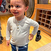 Louis a rejoint le concours — aidez-le/la à gagner de superbes lots ! blue_pants, buttoned_shirt, cabinet, casual_clothing, child, face, floor_tiles, happy, indoor, light_skin, person, playful, shoes, short_hair, smiling, standing, white_shirt, wood_floor, wooden_cabinet, young_child