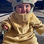 baby, child, costume, baby_yoda, smiling, cute, indoors, floor, carpet, yellow_clothing, hat, ears, plush, happy, portrait, person, toddler, cozy, warm_clothing, playful