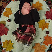 Lyana participe au concours pour gagner de l'argent avec cette photo : baby, infant, sleeping, blanket, autumn, fall_leaves, leaves, nature, outdoor, plaid_skirt, headwrap, black_clothing, soft_texture, peaceful, seasonal, cozy, child, portrait, cute, resting