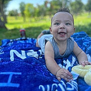 Azariah joined the competition — help win amazing prizes! baby, smiling, outdoor, blanket, grass, blue_sky, happy, child, infant, nature, playful, cute, young_child, portrait, sunlight, daytime, clothing, relaxing, toy, face