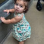 toddler, child, barefoot, curly_hair, blue_eyes, dress, standing, concrete, floor, leaning, expression, portrait, outdoor, casual_clothing, baby, person, young_child, cute, curiosity, natural_light