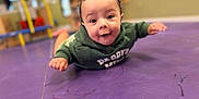 Wayland is registered to the contest to win money with this photo: baby, casual_clothing, child, curly_hair, cute, expression, face, floor, happy, head, hoodie, indoor, infant, person, playroom, portrait, purple_mat, skin, smiling, young_child