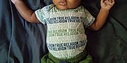 Kyrie is registered to the contest to win money with this photo: baby, infant, child, clothing, hat, pants, shirt, lying_down, blanket, pacifier, green, white_socks, portrait, cute, indoors, young_child, face, expression, relaxed, casual