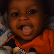 Hayden joined the competition — help win amazing prizes! baby, child, smiling, closeup, face, orange_shirt, blanket, happy, infant, portrait, cute, young, indoor, person, expression, joyful, cozy, warm, playful, toddler