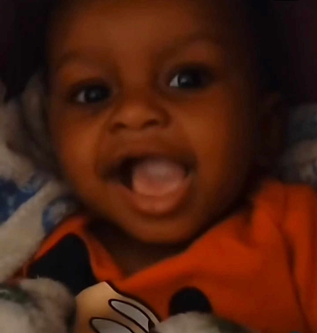 Hayden joined the competition — help win amazing prizes! baby, child, smiling, closeup, face, orange_shirt, blanket, happy, infant, portrait, cute, young, indoor, person, expression, joyful, cozy, warm, playful, toddler