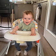 Scott joined the competition — help win amazing prizes! baby, walker, smiling, indoor, kitchen, high_chair, cabinet, floor, window, child, person, clothing, socks, face, hair, furniture, toy, happy, home, light
