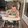 baby, cabinet, child, clothing, face, floor, furniture, hair, happy, high_chair, home, indoor, kitchen, light, person, smiling, socks, toy, walker, window