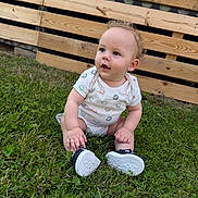 Kingston is registered to the contest to win money with this photo: baby, child, infant, sitting, grass, outdoor, wooden_fence, backyard, onesie, smiley_pattern, shoes, white_shoes, portrait, face, blue_eyes, blond_hair, curious, happy, lawn, daylight