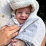 baby, child, smile, hood, blanket, hand, adult_hand, knit_sweater, outdoor, nature, greenery, portrait, face, warm_clothing, cozy, infant, cute, holding, closeup, happy