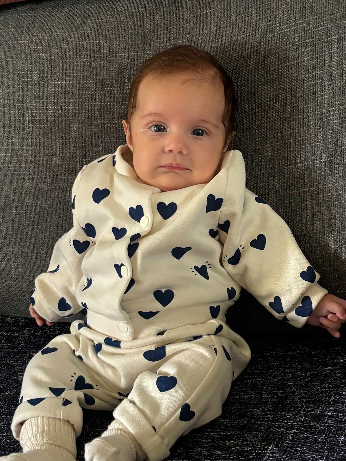 Camille a rejoint le concours — aidez-le/la à gagner de superbes lots ! baby, infant, child, couch, clothing, heart_pattern, sitting, portrait, face, eyes, socks, cozy, indoors, fabric, cute, expression, young_child, casual, relaxed, home