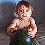 baby, child, watermelon, fruit, curious, wide_eyes, shirtless, sitting, indoor, soft_background, light_skin, brown_hair, hands, large_object, grip, portrait, infant, cute, expression, food