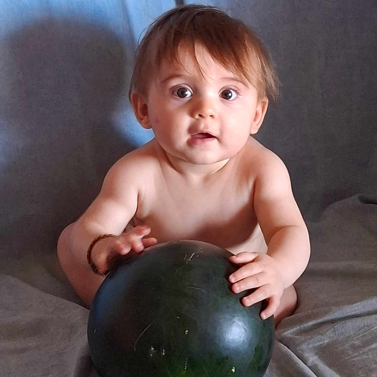 Djovani participe au concours pour gagner de l'argent avec cette photo : baby, brown_hair, child, curious, cute, expression, food, fruit, grip, hands, indoor, infant, large_object, light_skin, portrait, shirtless, sitting, soft_background, watermelon, wide_eyes
