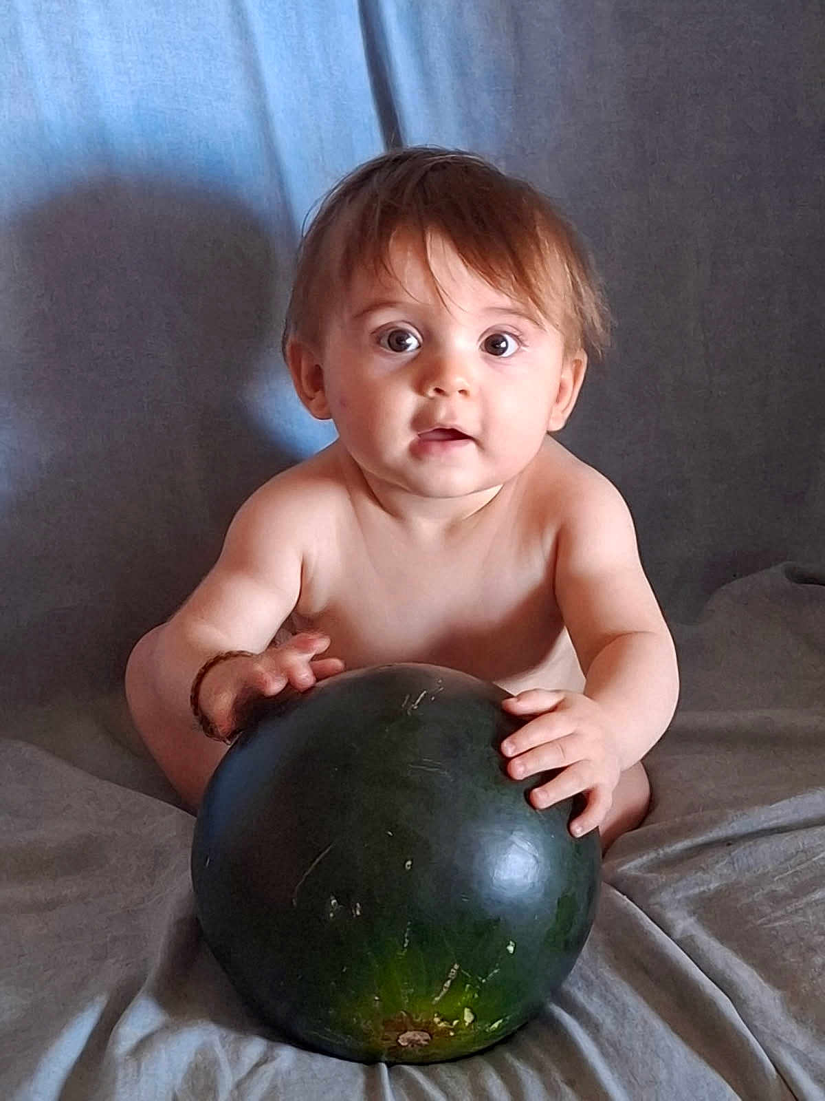Djovani participe au concours pour gagner de l'argent avec cette photo : baby, child, watermelon, fruit, curious, wide_eyes, shirtless, sitting, indoor, soft_background, light_skin, brown_hair, hands, large_object, grip, portrait, infant, cute, expression, food